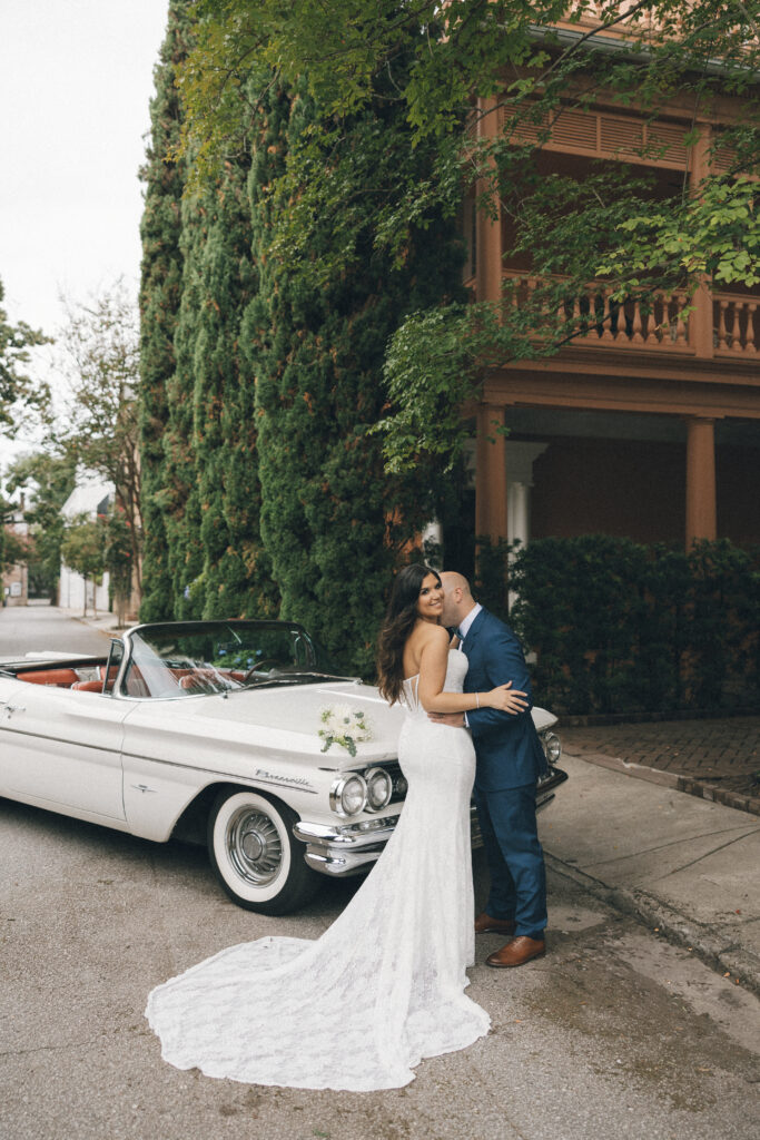 A bride and groom pose with the classic car they rented for their Charleston, SC wedding.