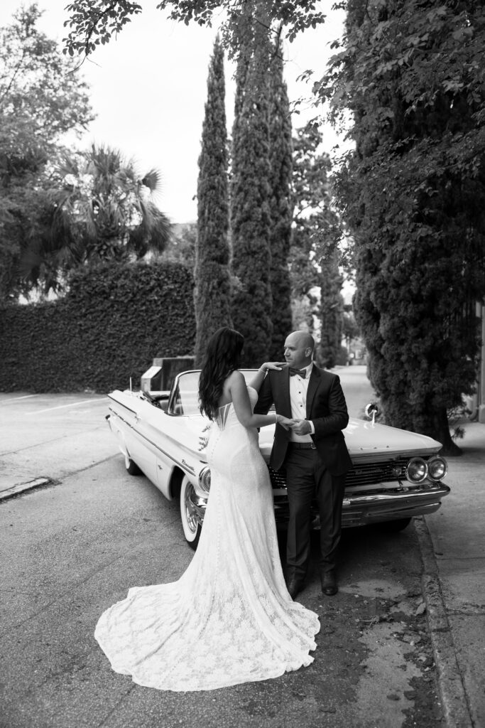 A bride and groom pose in front of the classic car they rented for their Charleston, SC wedding.