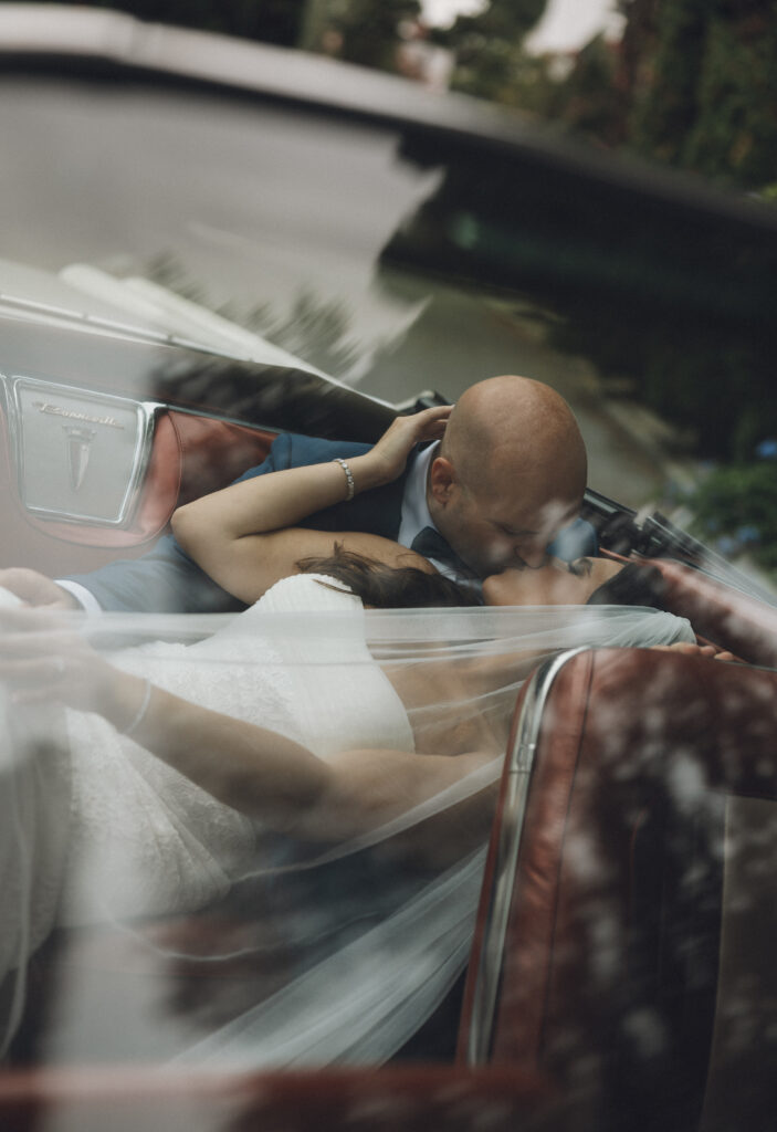 A bride and groom share a kiss in the classic car they rented for their Charleston, SC wedding.