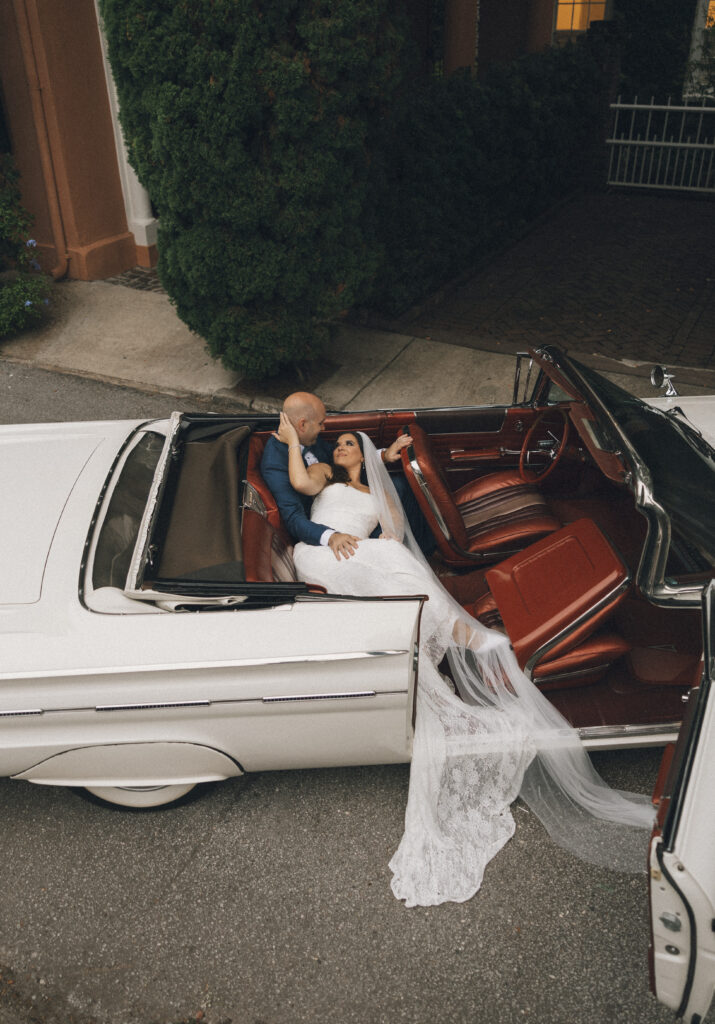 A bride and groom pose in the classic car they rented for their Charleston, SC wedding.