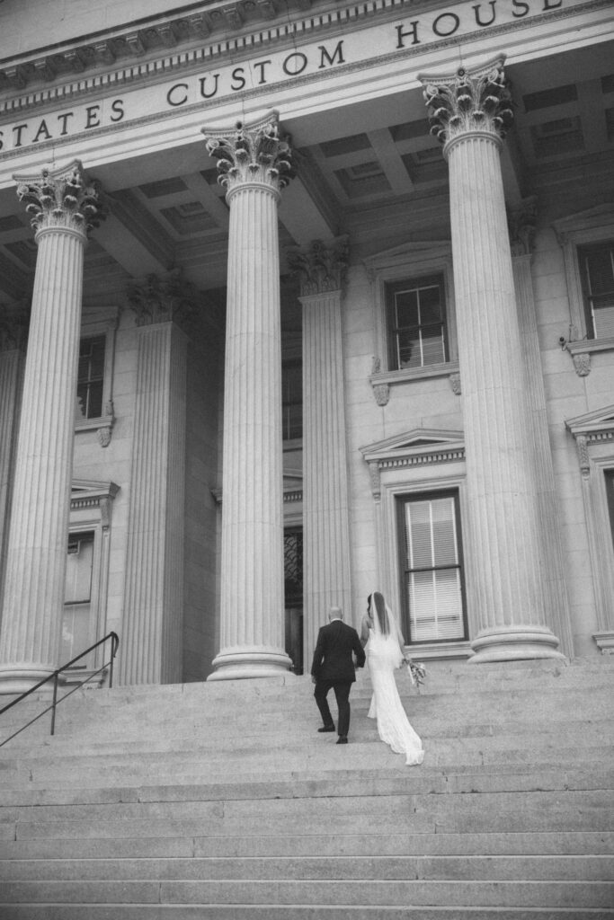 A bride and groom on the steps of a building in downtown Charleston, SC.