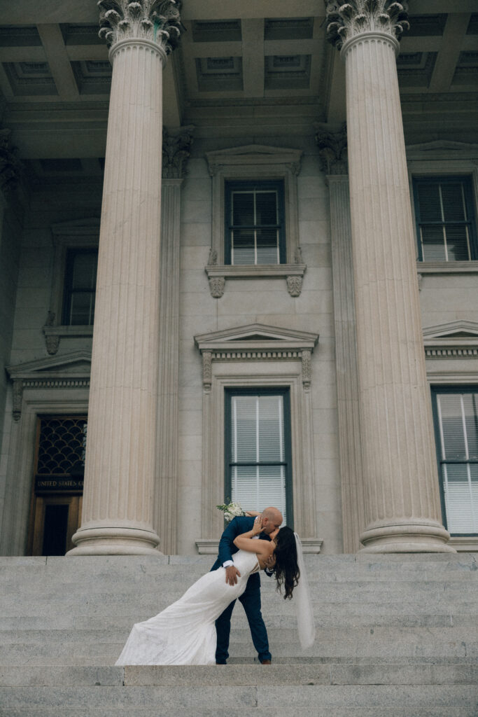 A bride and groom share a kiss on the steps of a historic building in downtown Charleston, SC.