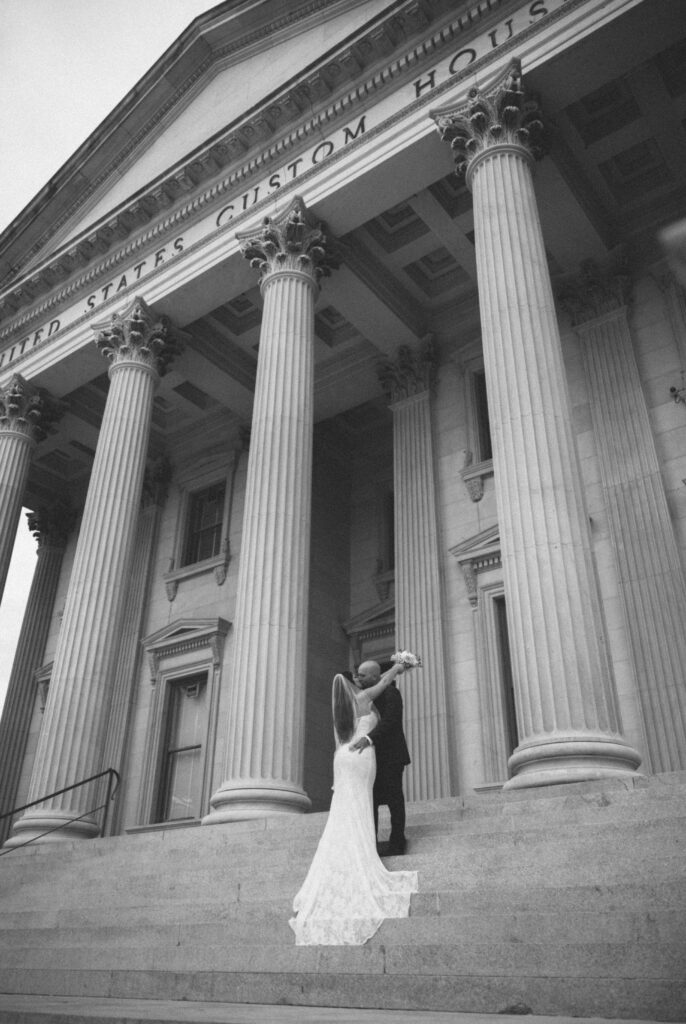 A bride and groom share a kiss on the steps of a building in downtown Charleston, SC.