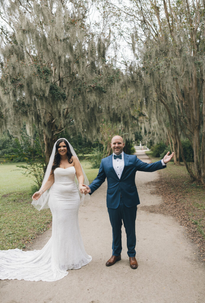 Portraits of the bride and groom in front of the Spanish moss-covered trees in Charleston, SC.