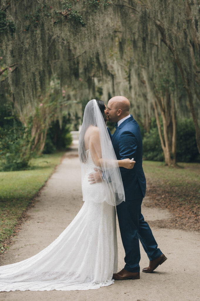 A bride and groom sharing a kiss under the Spanish moss-covered trees in Charleston, SC.