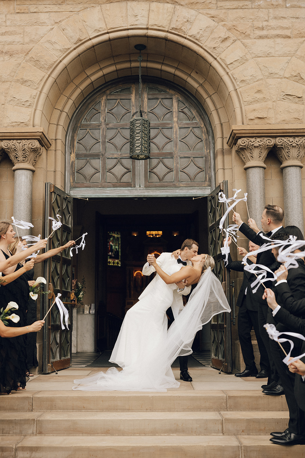 A bride and groom share a kiss on Cathedral stairs after their ceremony.