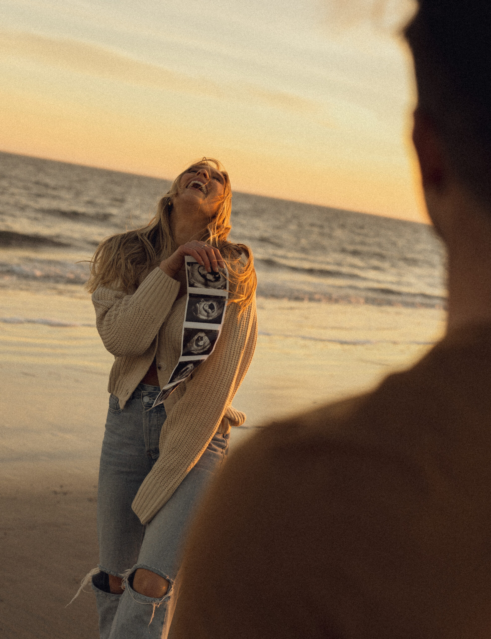 A couple poses for their pregnancy announcement photos on a beach in Charleston, SC.